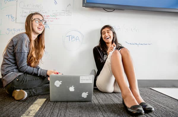 Deux femmes riant lors d'une réunion avec ordinateur portatif